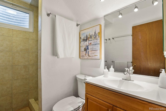 bathroom featuring vanity, toilet, and a tile shower