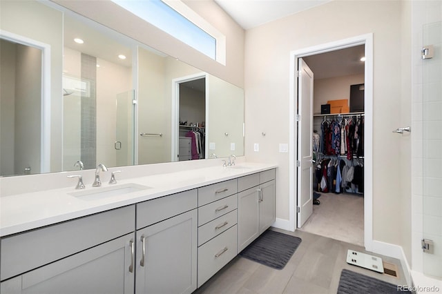 full bath featuring a stall shower, a sink, a spacious closet, and double vanity