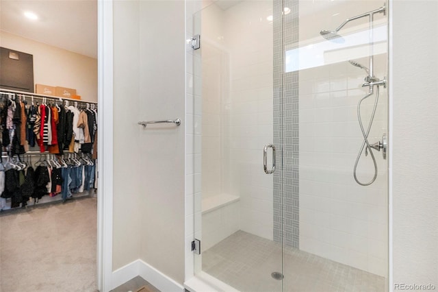 bathroom with a stall shower, a walk in closet, and baseboards