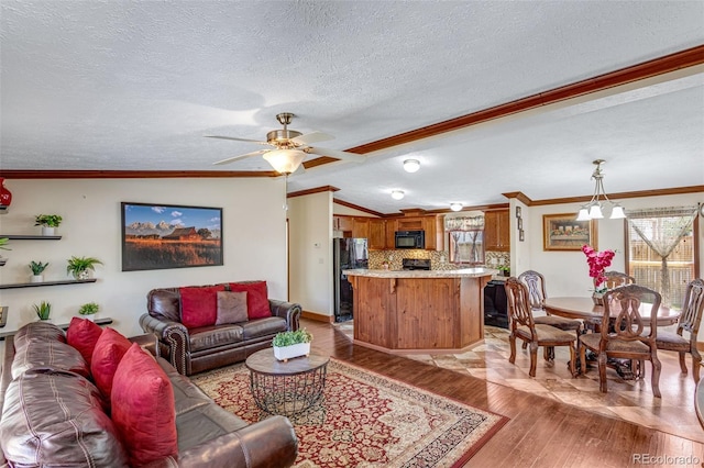 1214 Mac Kay Ct, Dacono, CO 80514 - living room featuring a textured ceiling, ornamental molding, light wood finished floors, vaulted ceiling, and ceiling fan