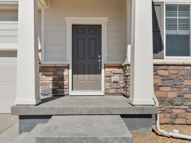 view of exterior entry with stone siding and a garage