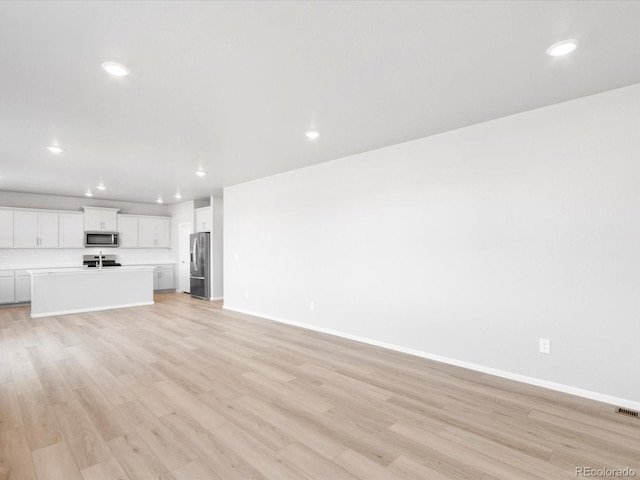 unfurnished living room featuring recessed lighting, baseboards, and light wood-style flooring