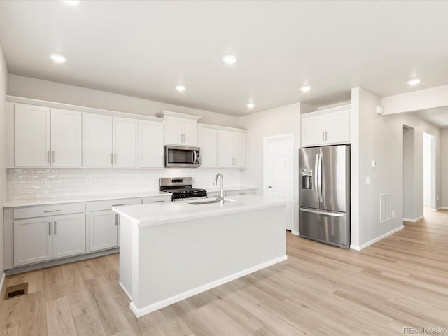 kitchen with a sink, visible vents, light wood finished floors, and stainless steel appliances