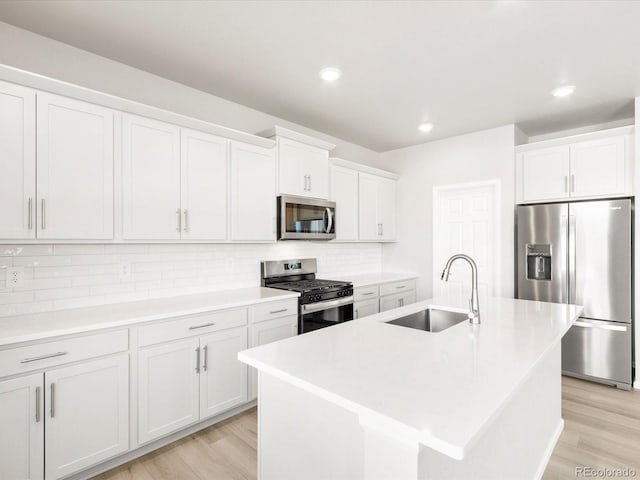 kitchen with light wood-type flooring, a sink, backsplash, appliances with stainless steel finishes, and light countertops