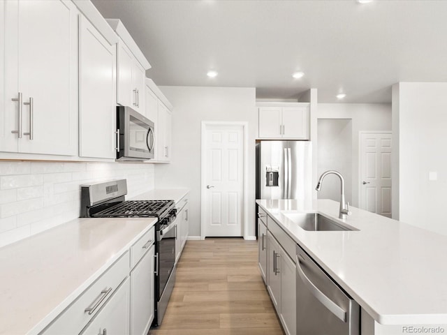 kitchen with light wood-type flooring, a sink, backsplash, stainless steel appliances, and light countertops