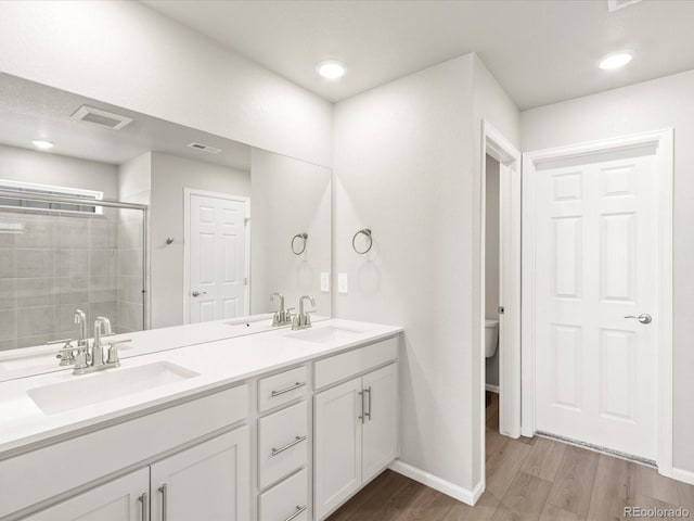 bathroom featuring a sink, visible vents, wood finished floors, and a shower stall