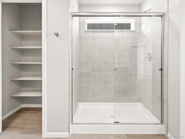 bathroom featuring a shower stall, baseboards, and wood finished floors