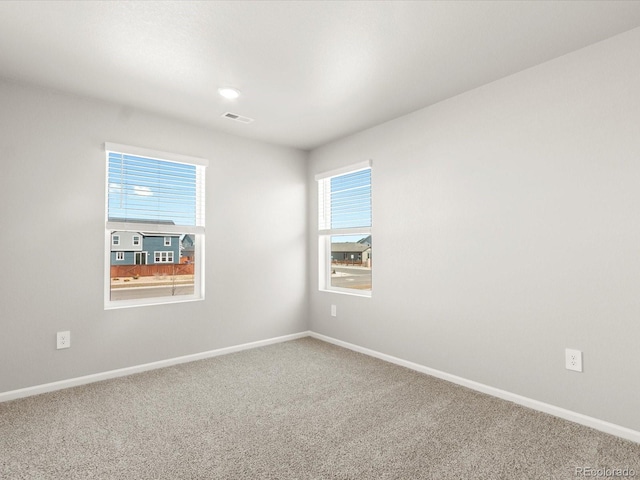 carpeted empty room with visible vents, plenty of natural light, and baseboards