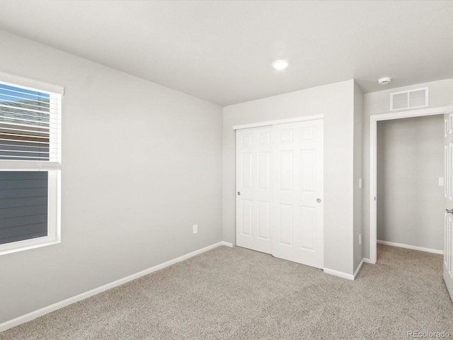 unfurnished bedroom with a closet, visible vents, baseboards, and carpet floors