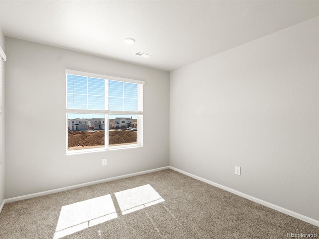 spare room featuring carpet flooring, baseboards, and visible vents