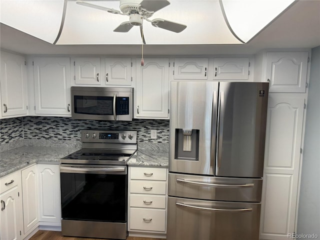 kitchen featuring appliances with stainless steel finishes, white cabinetry, light stone countertops, and ceiling fan