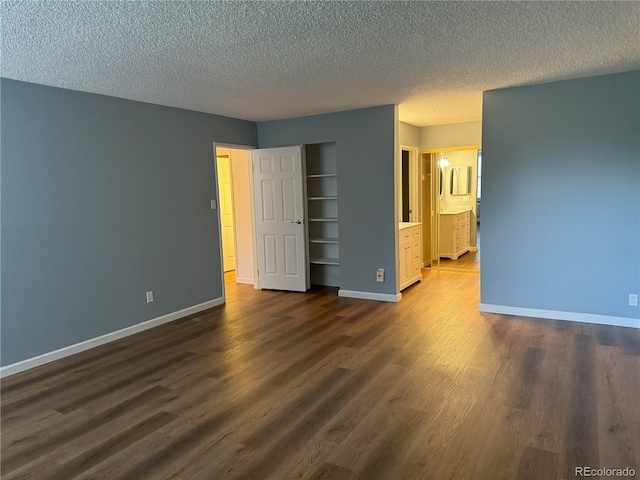 unfurnished bedroom with a textured ceiling, connected bathroom, and dark hardwood / wood-style floors