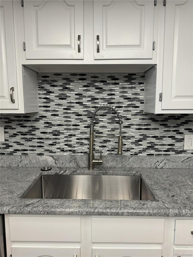 kitchen with white cabinets, stone counters, tasteful backsplash, and sink