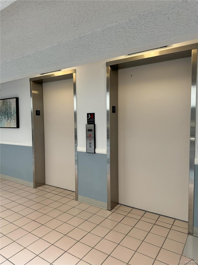 unfurnished room featuring light tile patterned floors, elevator, and a textured ceiling