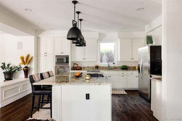 301 Fairfax St, Denver, CO 80220 - kitchen featuring appliances with stainless steel finishes, dark wood finished floors, a kitchen bar, white cabinets, and recessed lighting
