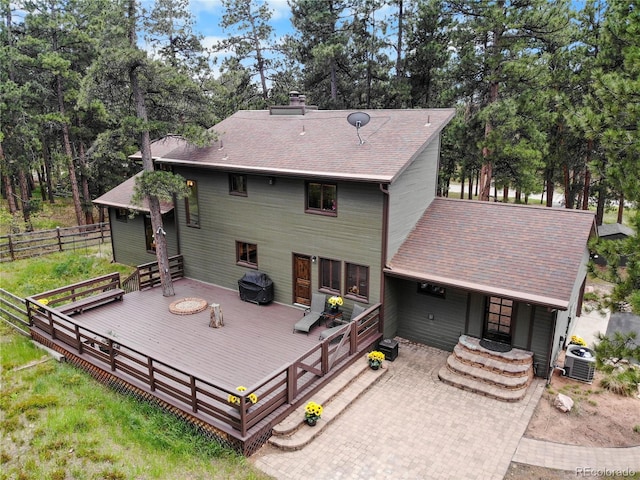 4515 Red Rock Dr, Larkspur, CO 80118 - back of house featuring central air condition unit, a shingled roof, a wooden deck, a chimney, and view of scattered trees