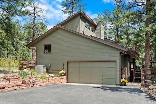 4515 Red Rock Dr, Larkspur, CO 80118 - view of side of home featuring a chimney, driveway, cooling unit, and a garage