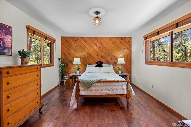 4515 Red Rock Dr, Larkspur, CO 80118 - bedroom with baseboards, an accent wall, wood walls, and wood finished floors