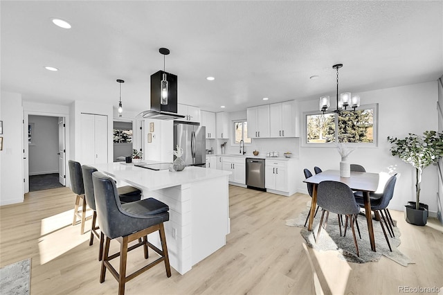 kitchen with an inviting chandelier, light hardwood / wood-style flooring, hanging light fixtures, appliances with stainless steel finishes, and white cabinets