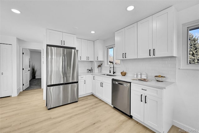 kitchen with appliances with stainless steel finishes, white cabinets, tasteful backsplash, and sink