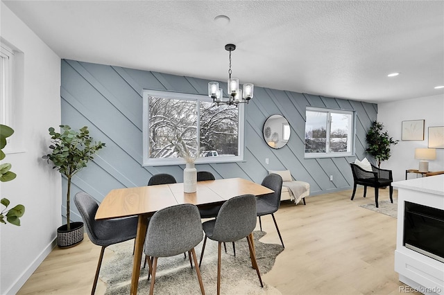 dining area with a textured ceiling, light hardwood / wood-style flooring, and a chandelier