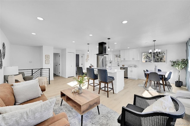 living room with light wood-type flooring, a chandelier, and sink