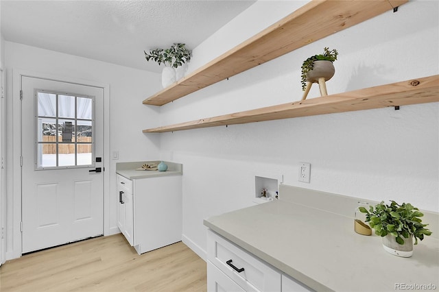 laundry room with light hardwood / wood-style flooring, hookup for a washing machine, and cabinets