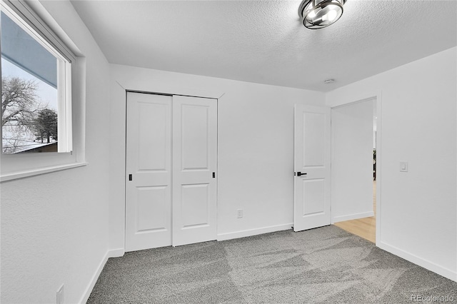 unfurnished bedroom featuring a closet, a textured ceiling, and carpet flooring