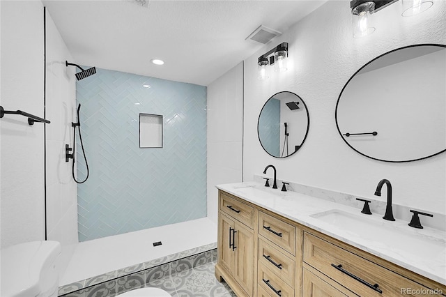 bathroom featuring a tile shower, tile patterned floors, and vanity