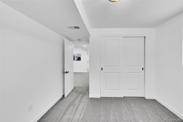 interior space featuring carpet floors, a textured ceiling, and a closet