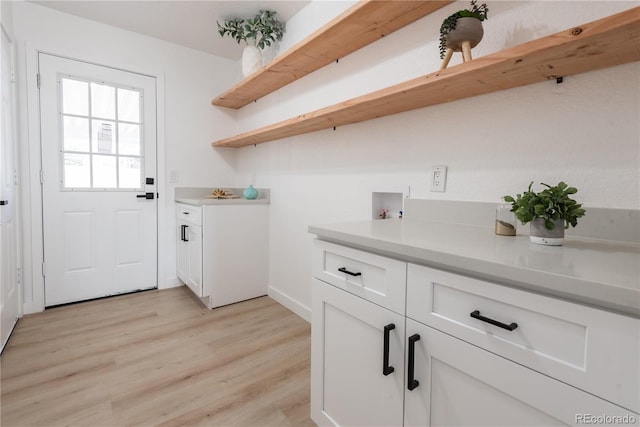 washroom with washer hookup, light hardwood / wood-style floors, and cabinets