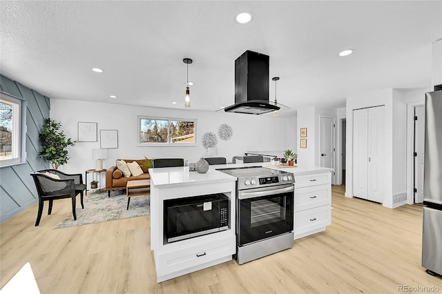 kitchen featuring white cabinetry, hanging light fixtures, island exhaust hood, stainless steel appliances, and light hardwood / wood-style flooring