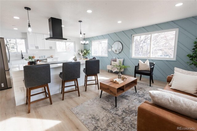 living room with plenty of natural light, a notable chandelier, and light hardwood / wood-style flooring