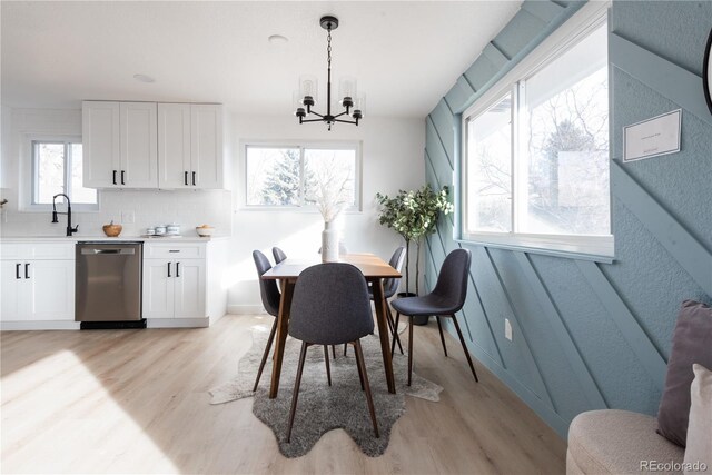 dining area featuring sink, a chandelier, and light hardwood / wood-style flooring