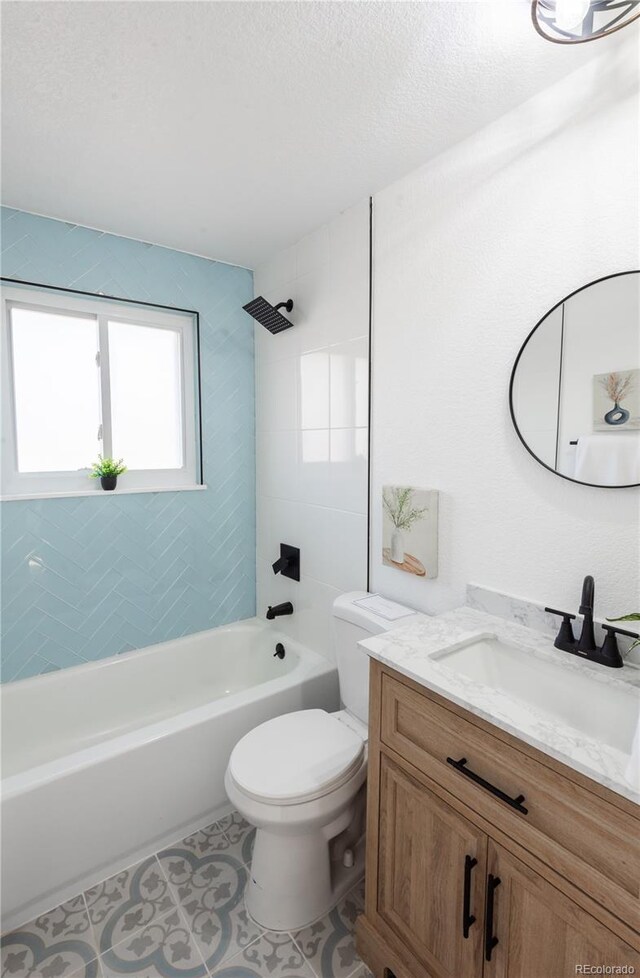 full bathroom with vanity, a textured ceiling, tiled shower / bath, tile patterned floors, and toilet