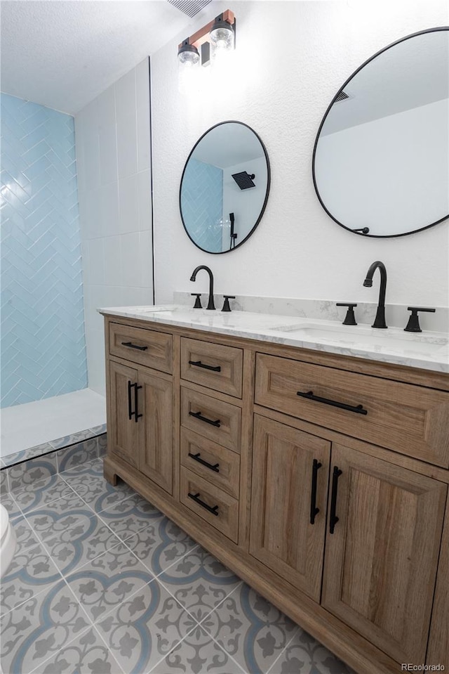 bathroom featuring vanity, tiled shower, and tile patterned floors