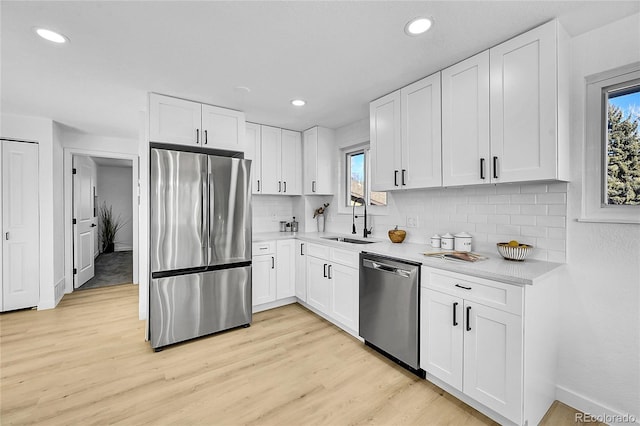 kitchen with light wood-style flooring, a sink, light countertops, white cabinets, and appliances with stainless steel finishes