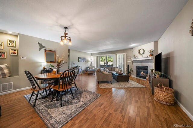 23712 Pondview Pl Unit A, Golden, CO 80401 - dining space featuring a tile fireplace, wood finished floors, a textured ceiling, and a chandelier