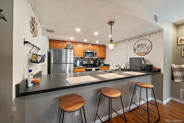 23712 Pondview Pl Unit A, Golden, CO 80401 - kitchen featuring stainless steel appliances, a peninsula, wood finished floors, a kitchen bar, and recessed lighting