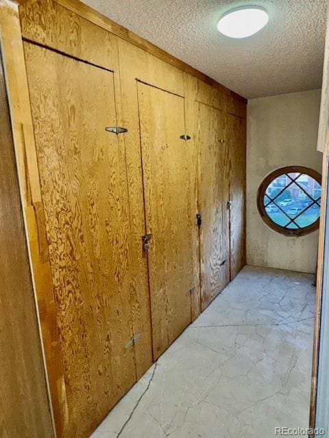 corridor with a textured ceiling and wood walls