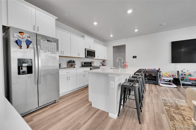 kitchen with tasteful backsplash, light wood-type flooring, appliances with stainless steel finishes, white cabinetry, and a sink