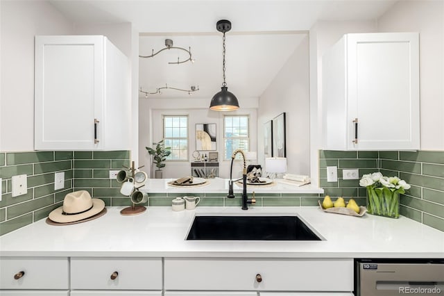 kitchen with pendant lighting, dishwasher, white cabinetry, and sink