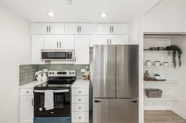 kitchen featuring white cabinets, light wood-type flooring, stainless steel appliances, and tasteful backsplash