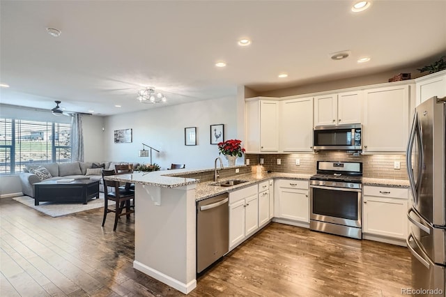 kitchen with white cabinets, dark hardwood / wood-style flooring, kitchen peninsula, and stainless steel appliances