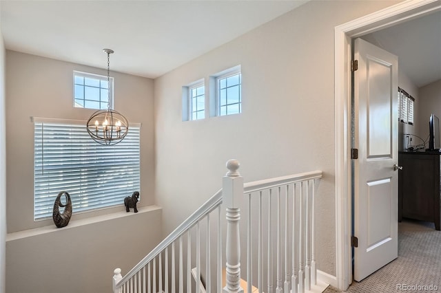 hall featuring carpet flooring and a chandelier