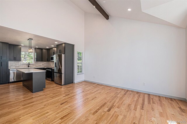 9948 King St, Westminster, CO 80031 - kitchen featuring appliances with stainless steel finishes, light countertops, light wood-style floors, tasteful backsplash, and a kitchen island