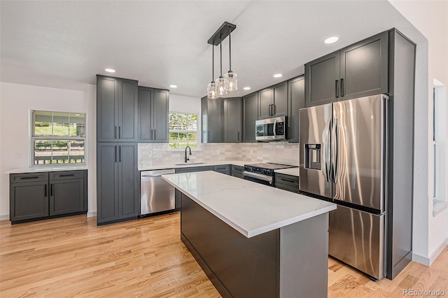 9948 King St, Westminster, CO 80031 - kitchen with stainless steel appliances, light wood finished floors, tasteful backsplash, decorative light fixtures, and a kitchen island