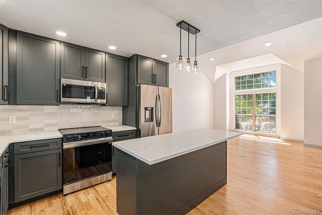 9948 King St, Westminster, CO 80031 - kitchen with stainless steel appliances, light wood finished floors, tasteful backsplash, decorative light fixtures, and light stone counters