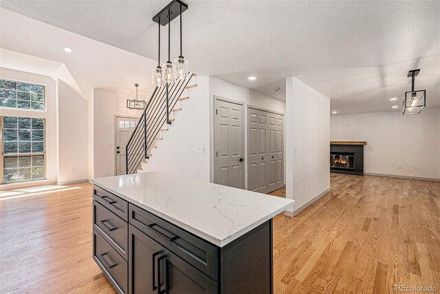 9948 King St, Westminster, CO 80031 - kitchen featuring open floor plan, light wood-style flooring, a brick fireplace, hanging light fixtures, and recessed lighting