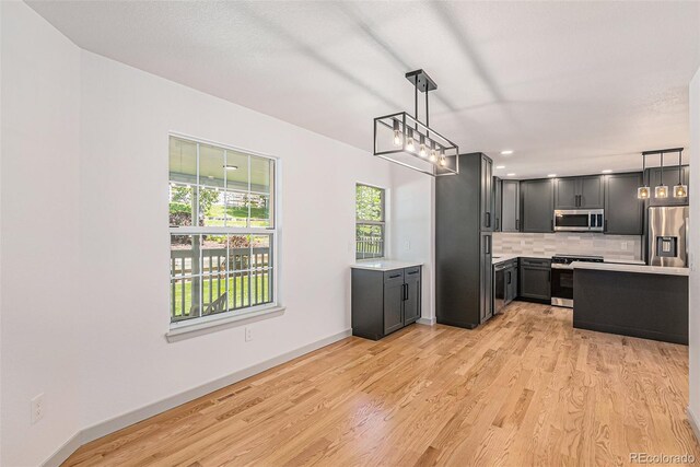 9948 King St, Westminster, CO 80031 - kitchen with stainless steel appliances, light countertops, light wood-type flooring, tasteful backsplash, and decorative light fixtures